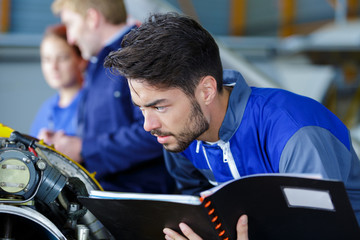 portrait of smiling mechanic in workshop holding book