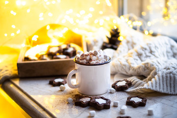 Obraz na płótnie Canvas Comforting Christmas food, mug of hot cocoa with marshmallow and cookies with cozy lights