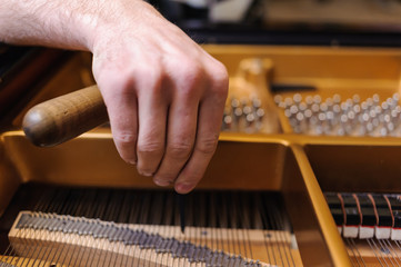 Man tuning traditional upright piano for jazz. hand of a man tuning piano, close up