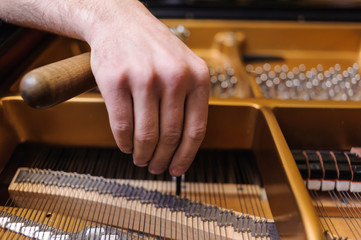 Man tuning traditional upright piano for jazz. hand of a man tuning piano, close up