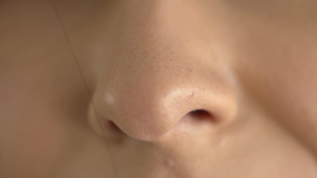 Extreme macro close up of a woman's nose while breathing in fresh air