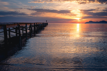 Fototapeta na wymiar Schwimmer auf Steg am Strand zum Sonnenaufgang