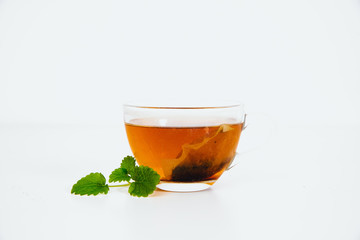 Lemon balm and brewed lemon balm in cup on white background. The concept of using herbs and spices at home. Herb for calming down.