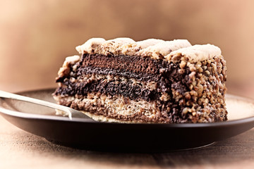 Piece of Chocolate Cake on plate. Rustic wooden background. Close up.