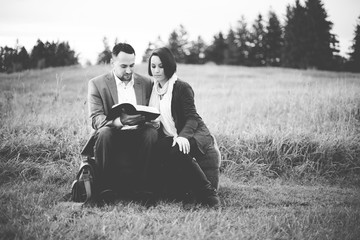 Grayscale shot of a couple sitting and reading the bible
