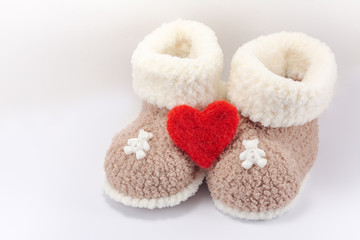 knitted baby booties for newborn with woolen heart on light background