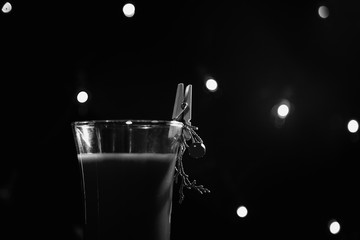 black and white photo new year's glass with drink, cocktail decorated in new year's style, branch, clothespin and berry, on a dark background