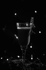 black and white photo new year's glass with drink, cocktail decorated in new year's style, branch, clothespin and berry, on a dark background