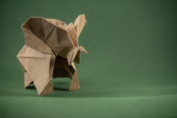 origami baby elephant made of craft paper on green background, paper and forest conservation concept, save paper save the forest, mockup, copy space