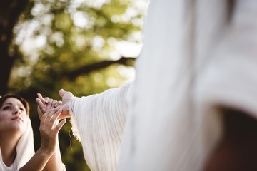 Shallow focus shot of a female grabbing the hand of Jesus Christ for healing and help