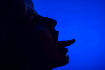 Woman's face with tongue silhouette in front of blue background