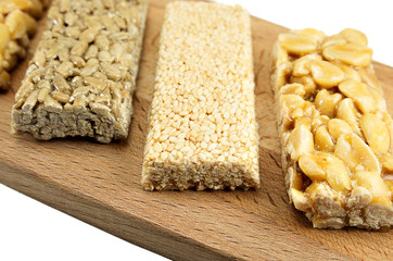 different kinds of kozinaks on wooden Board on white isolated background, kozinak sunflower peanut sesame, Oriental sweets, brittles