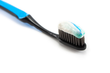 black toothbrush with the minty color of toothpaste on a light background