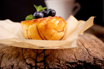 Blueberry muffin and berries with a cup of tea on an old wooden board