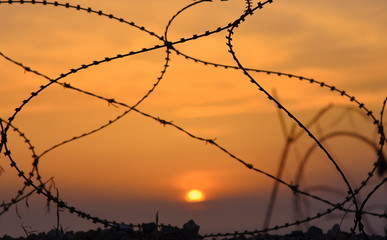 Stacheldraht mit flammendem Sonnenuntergang im Hintergrund