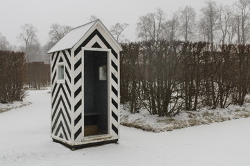 Black and white striped guardhouse in the middle of a snowy park