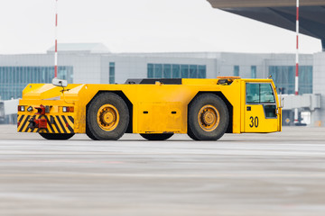 Airplane yellow pushback truck in moving at airport. Special, low profile vehicle - pushback...