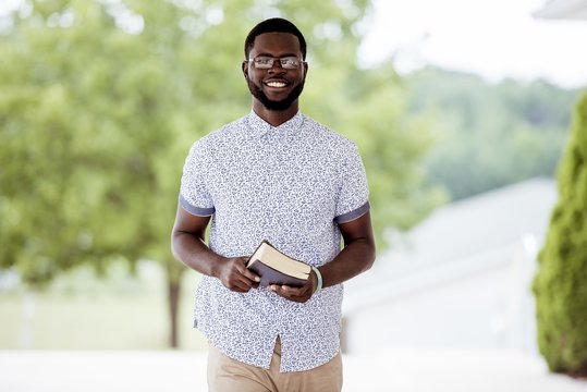 Shallow focus shot of a male standing while holding the bible and looking at the camera