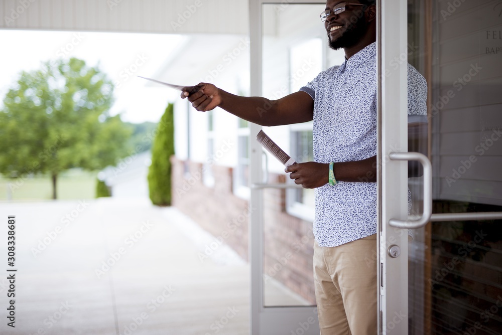 Wall mural shallow focus shot of a male standing near the door and giving out pamphlets