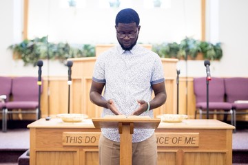 Shallow focus shot of a male reading bible near the wooden stand in the church