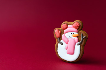 gingerbread cookie of cute snowman on red background. Traditional Christmas food. Christmas and New Year holiday concept.