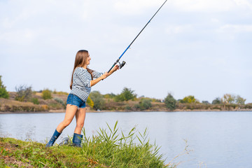 Beautiful young girl fishes on the lake.