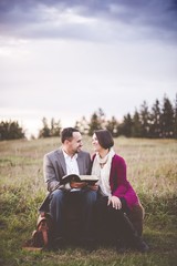 Vertical shot of a couple sitting and smiling at each other while holding the bible