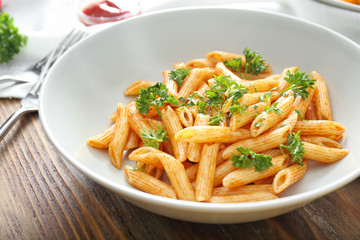 Plate with tasty pasta on wooden table