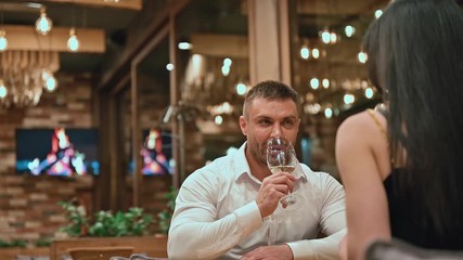 Romantic date in restaurant. Young couple in love drinking white wine in restaurant. Romantic relationship and dating concept