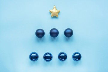 Blue Christmas toys in a shape of fir tree on blue background. Flat lay, top view festive holiday concept.