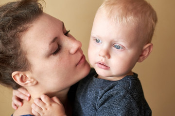 Portrait of a little boy hugging mom by the neck.