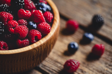 raspberries and blackberries on a wooden background in vintage style. Cutting board
