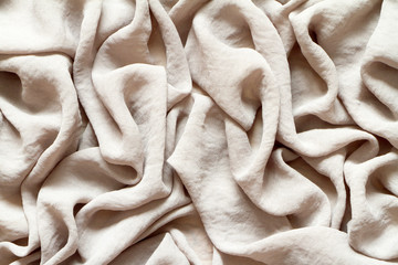 Folds of natural gray beige fabric, top view, background or concept.
