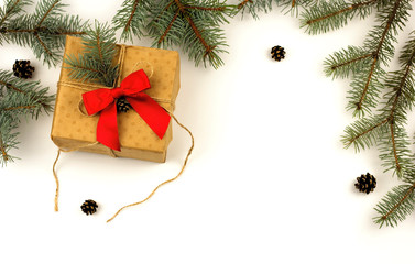 Gift Christmas box with a red bow and fir branches with cones on a white background. Flat lay, copy space.