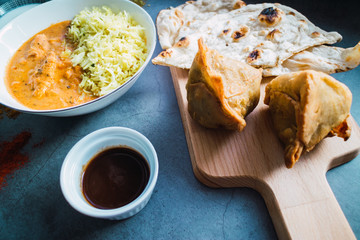 Traditional Indian cuisine. Samosas, Butter Chicken and Naan bread. Close up view.