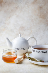 Cup of of tea with honey and teapot