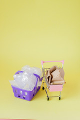 polythene and paper bags in a shopping basket on a yellow background
