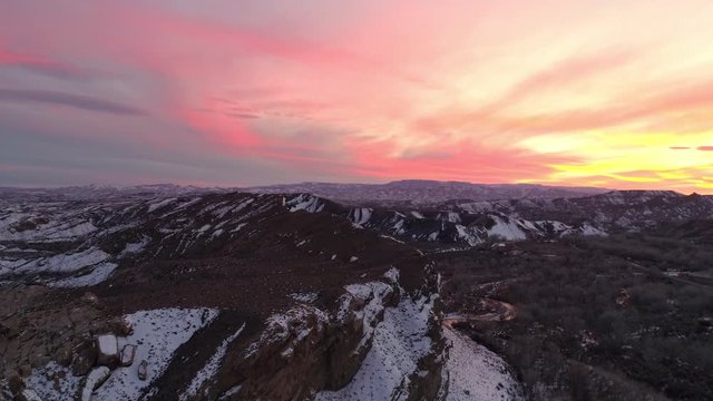 Aerial view of colorful sunset over the desert in winter with snow across the landscape in Utah.