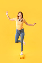 Stylish hipster girl with skateboard on color background