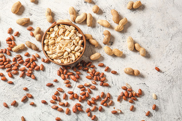 Bowl with peanuts on light background