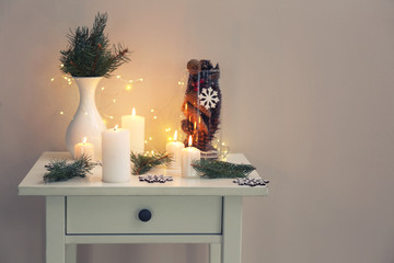 Beautiful burning candles and Christmas decor on table