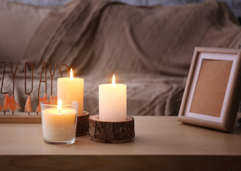 Beautiful burning candles and photo frame on table