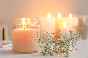 Beautiful burning candle and flowers on table