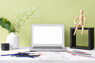 Comfortable workplace with laptop near color wall