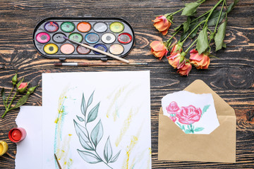 Set of artist's supplies and painting on wooden background