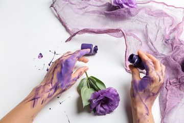 Artist's hands in paint, flowers and cloth on white background