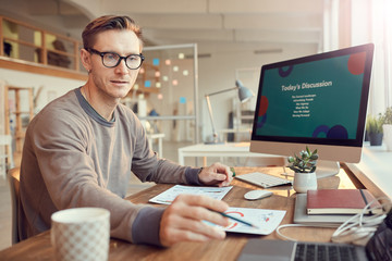 Portrait of handsome adult businessman preparing for presentation or online conference while...