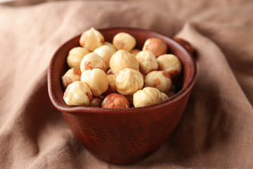 Jug with tasty hazelnuts on table