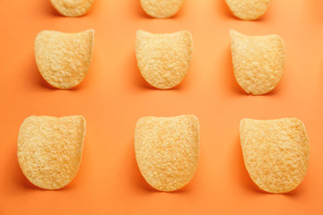 Tasty potato chips on color background