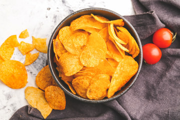 Tasty potato chips and tomatoes on table
